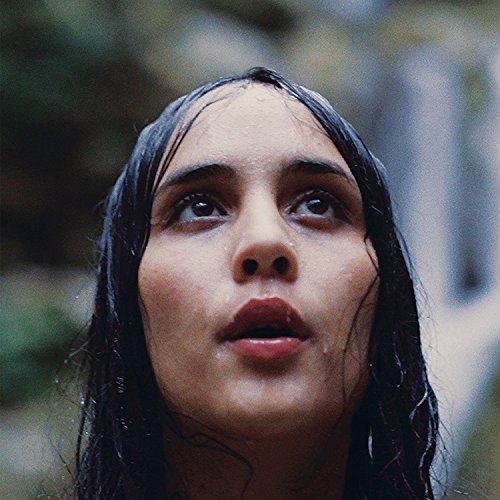 The image depicts a young woman with dark hair, gazing upwards with a surprised expression.