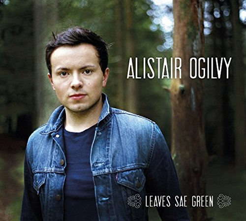 The alt text for the image is: "Man in denim jacket standing in front of trees, album cover."
