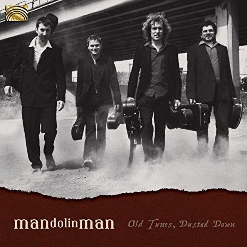 "Album cover featuring four men in suits holding instrument cases, walking in dusty road."