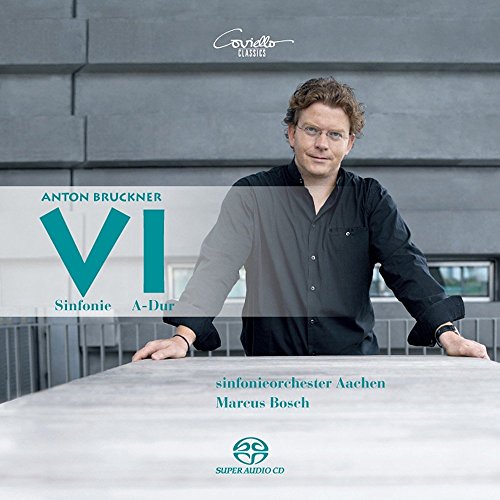 Man in black shirt stands behind a table, CD cover art.