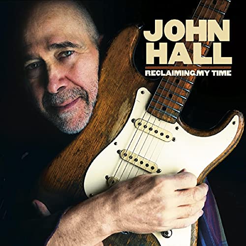 "Album cover featuring a man holding a guitar against a black background."