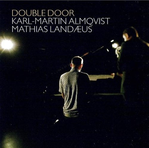 "Album cover featuring two men on stage with spotlights shining."