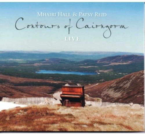 "CD cover featuring a piano on a hill overlooking a lake and mountains."