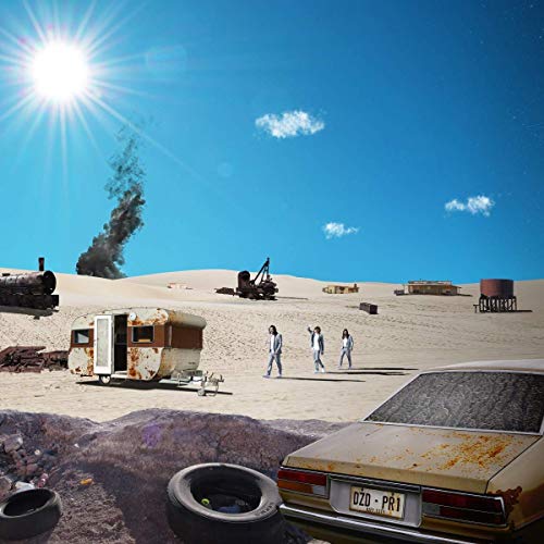 "Desert scene with rusty car, abandoned machinery, and three people in white suits walking."