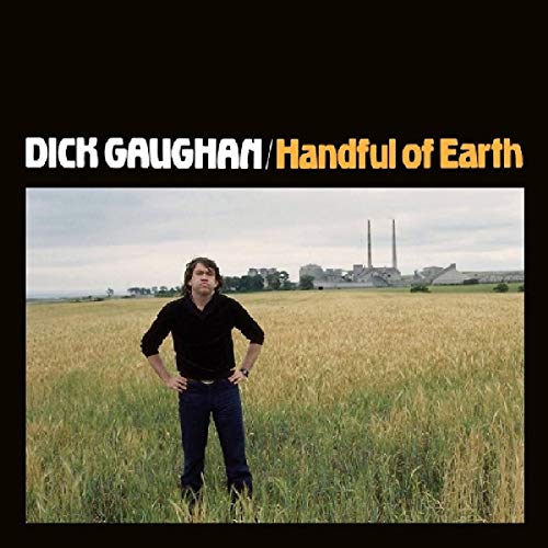 "Album cover with man standing in a field, industrial buildings in the background."
