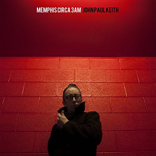 Album cover with man standing against a red-lit brick wall, wearing a dark hoodie.