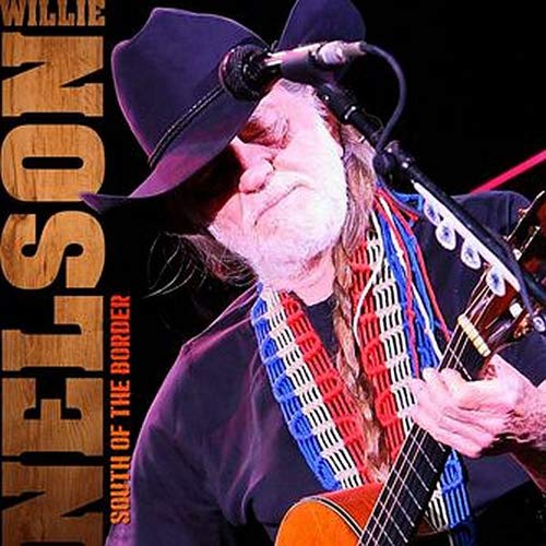 Willie Nelson playing guitar and singing into a microphone, wearing a cowboy hat.