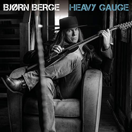 "Album cover featuring a man sitting in a chair holding a guitar."