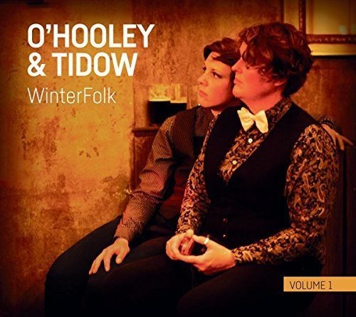 "Album cover featuring two men sitting together, wearing patterned shirts and black vests."