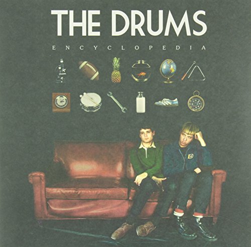 "Album cover with two men sitting on a red couch against a black background."