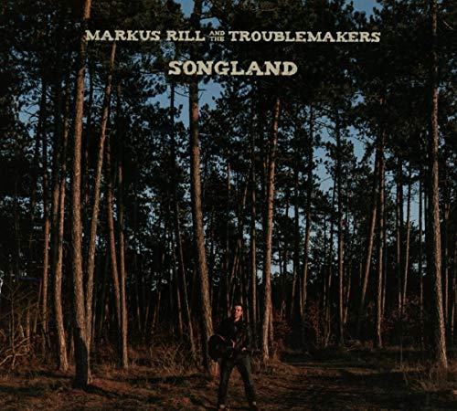 "Album cover with a man standing in a forest, holding a guitar."