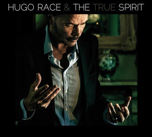 Album cover featuring a man in a suit, gesturing with his hands, against a dark background.