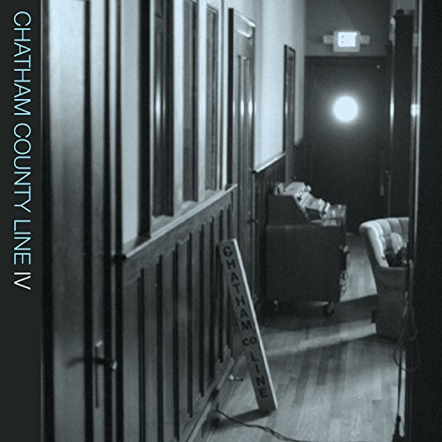 "Black and white photo of a dimly lit hallway with a sign."