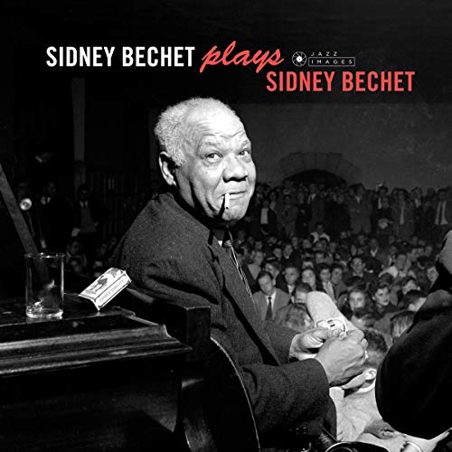 Black and white image of Sidney Bechet holding a soprano saxophone, with a crowd behind.