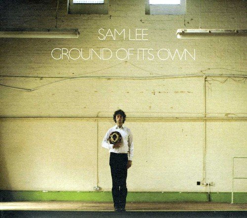 Album cover: man holding vinyl record in front of a concrete wall.