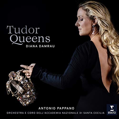"Diana Damrau in a black dress holding a crown against a black background."