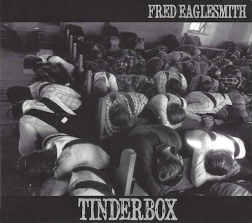 Black and white CD cover with men in a crowded room, heads down.