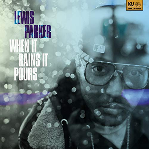 "Album cover featuring a man wearing glasses and a hat, surrounded by rain droplets."