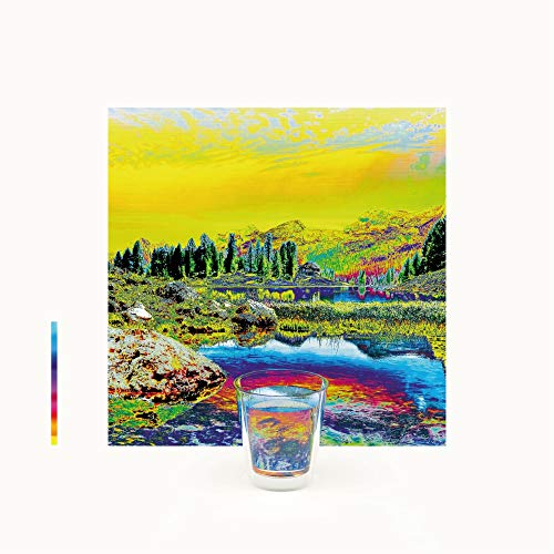 A glass is centered in front of a multicolored landscape painting.