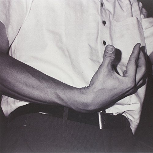 Black and white image of a man touching his chest near shirt pocket.