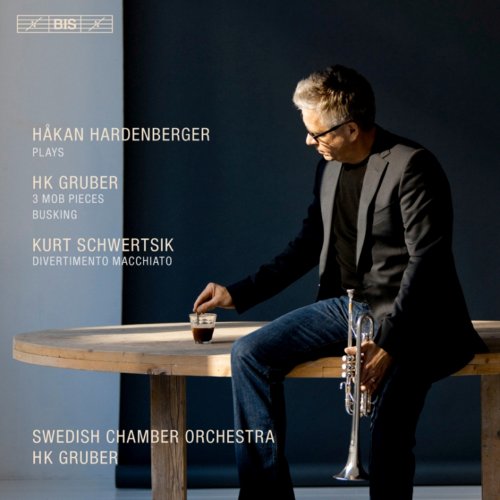 A man sits at a table, holding a trumpet, on a CD cover.