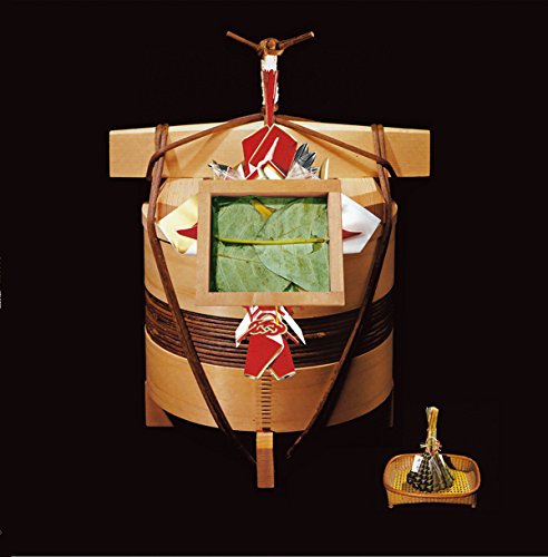 A wooden barrel with ornaments, containing a box of green leaves, against a black background.