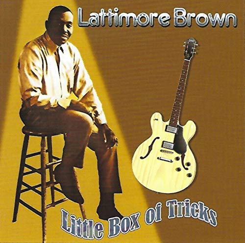 "Album cover with man sitting on stool next to a guitar, brown background."