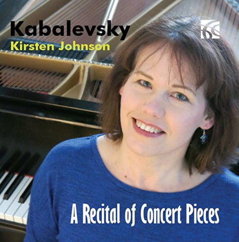 A woman in a blue shirt smiles in front of an open piano.