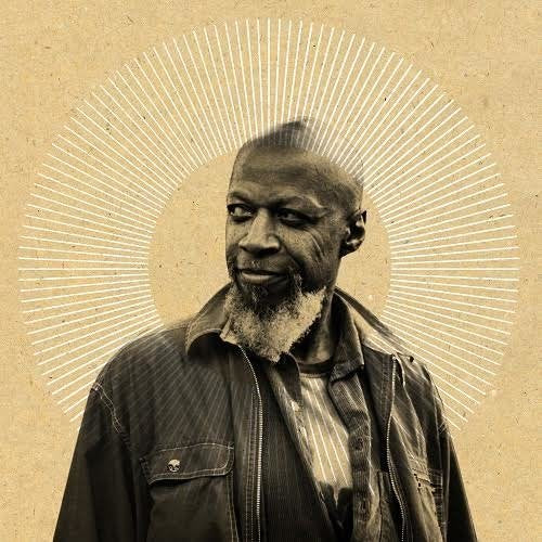 Portrait of Laraaji with radiating lines behind his head, sepia tone.