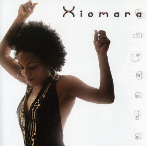 Woman with curly hair and black dress, arms raised, against a white background.