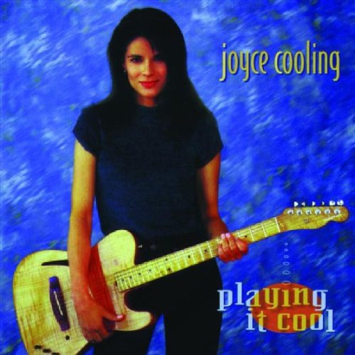 Woman with long dark hair holding a guitar against a blue background.