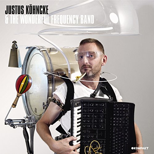 "Man in safety goggles holding synthesizer, with drum and maraca, on vinyl album cover."