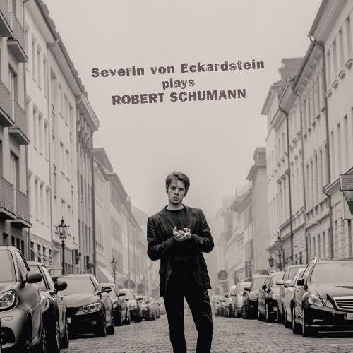 "Black and white CD cover with a man standing on a cobblestone street."