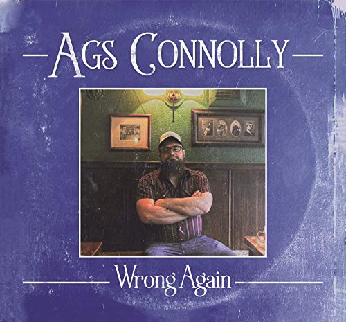 "Album cover with a man sitting, wearing a hat, on a blue background."