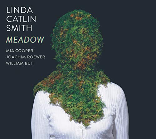 Album cover with a person covered in greenery against a dark background.