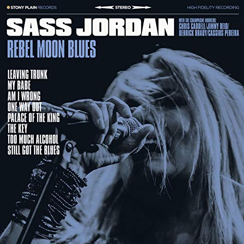 "Album cover featuring a woman with long hair holding a microphone, against a dark background."