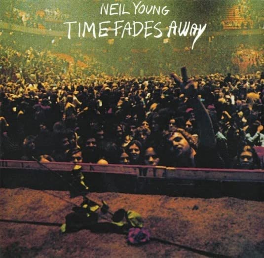 "Neil Young's 'Time Fades Away' album cover, featuring a crowd and abandoned guitar."