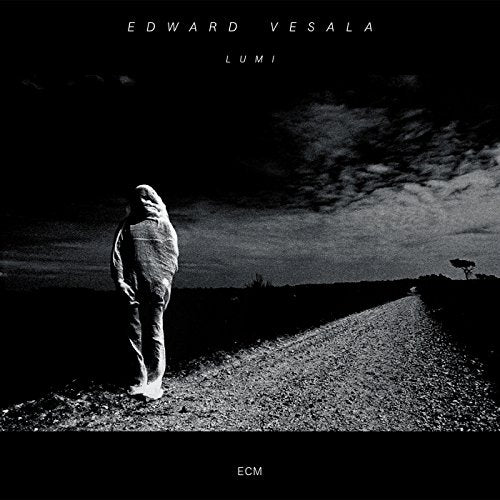 Black and white album cover with a person standing on a road at dusk.