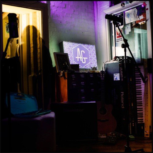"CD cover art: dimly lit studio with 'AG' sign on a table."