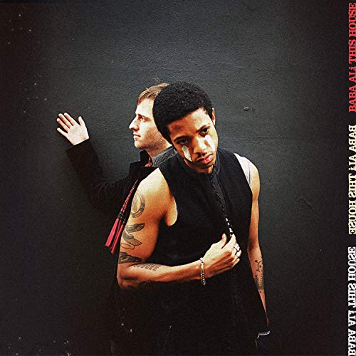 "Album cover featuring two men in black against a dark background, with red and white text."