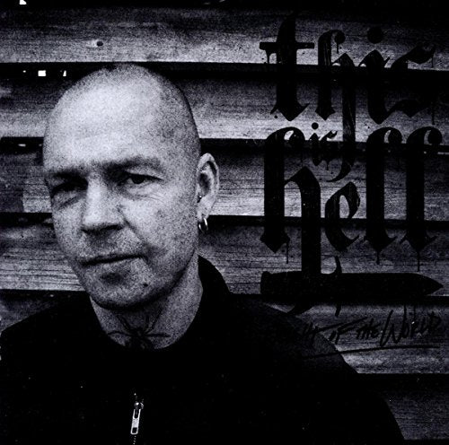 Black and white image of a man in front of a wooden wall with text.