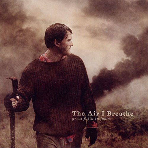 "Album cover: man with bloody face and gloves holding a cross, with smoke in background."