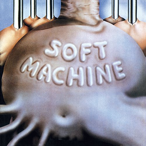 "CD cover with 'SOFT MACHINE' embossed on a metallic belly, surrounded by hands."