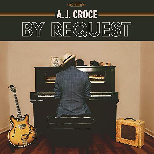 "Album cover: man in hat playing piano, guitar and amp nearby, beige background."