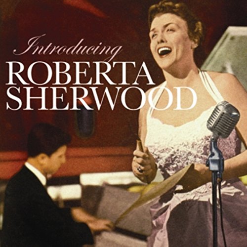 Woman singing into a microphone with a man playing piano beside her.