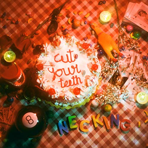 "Album cover art: 'Necking' with cake, 'cut your teeth' icing, on a checkered table."