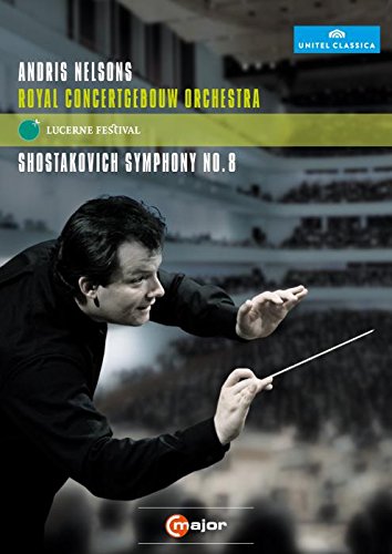 Conductor Andris Nelsons leads an orchestra, baton in hand, against a concert hall backdrop.