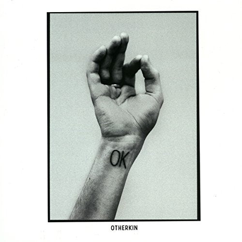 Black and white image of a hand with "OK" tattoo on the wrist.
