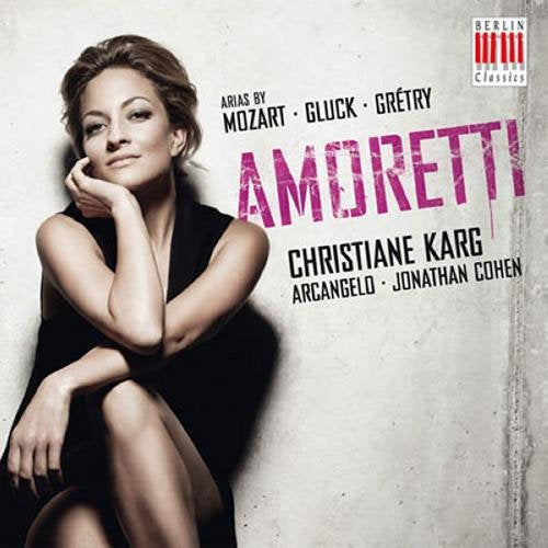 "CD cover featuring a woman in a black dress, sitting against a grey wall."