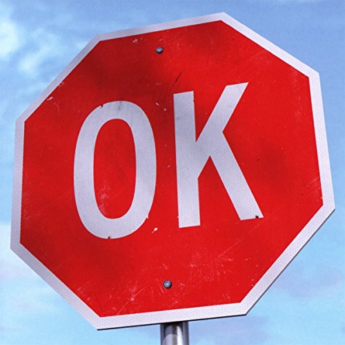 A red octagonal stop sign with "OK" in white letters against a blue sky.